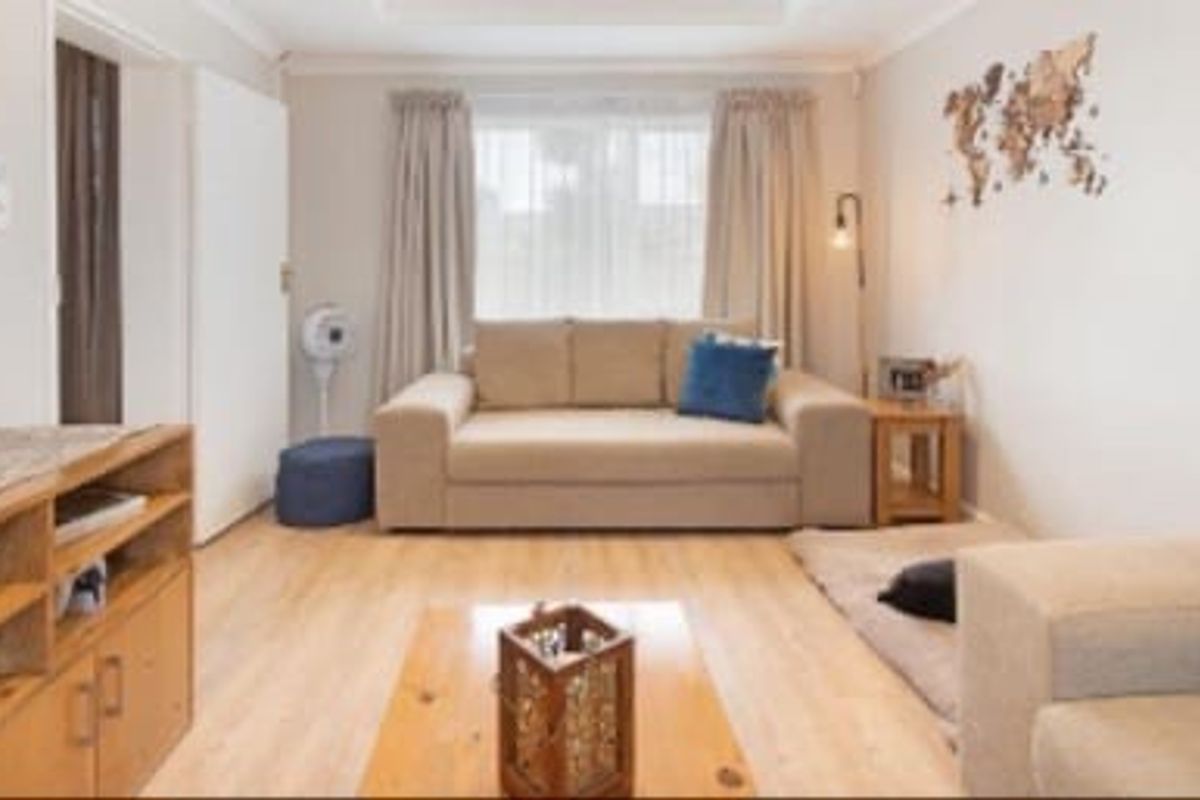 A comfortable living room featuring light-toned laminate flooring and neutral wall finishes, providing a bright and functional space for relaxation.
