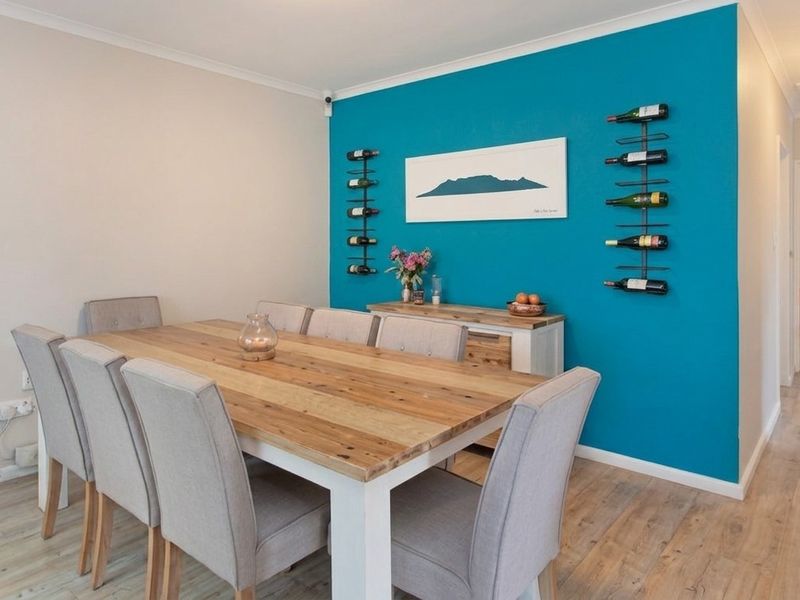A well-maintained dining room featuring light-toned laminate flooring, a vibrant blue accent wall, and neutral decor, creating a bright and inviting space.