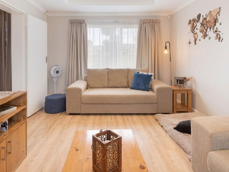 A well-maintained living room featuring light-toned laminate flooring and neutral wall finishes, creating a bright and comfortable atmosphere.