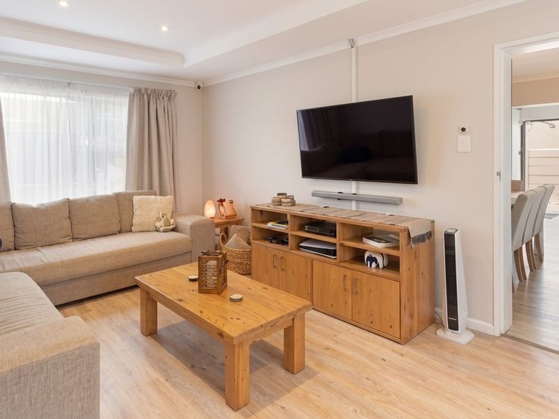 A well-maintained living room featuring laminate flooring, recessed ceiling lighting, and coving, offering a bright and comfortable space.