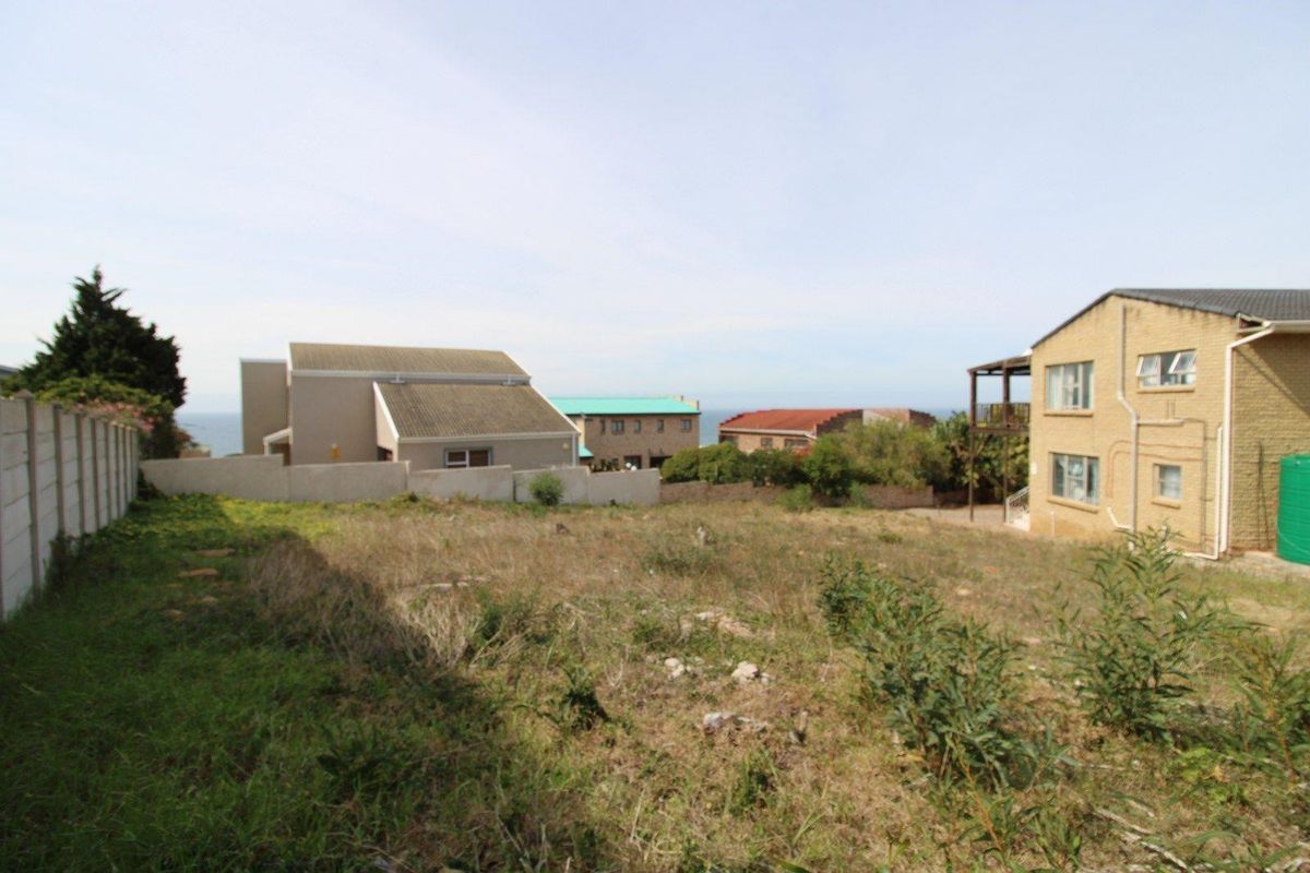 A vacant residential plot of land situated in a developed neighborhood with surrounding houses and partial sea views.