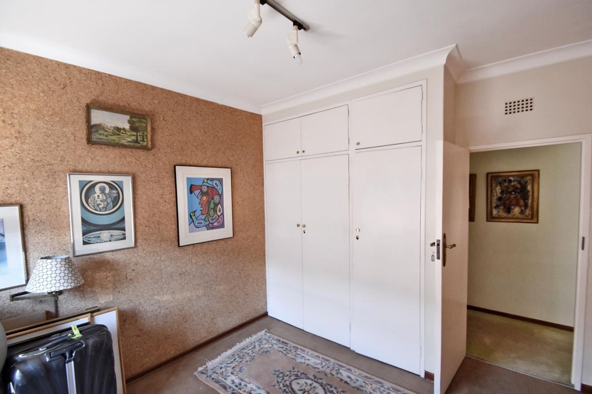 A bedroom featuring built-in floor-to-ceiling cupboards and distinctive cork wall cladding, offering functional storage space.