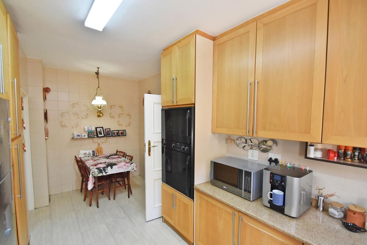 A functional kitchen featuring light wood cabinetry, stone countertops, and a built-in oven, with an adjacent dining area.