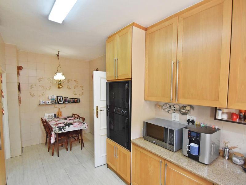 A functional kitchen featuring light wood cabinetry, stone countertops, and a built-in oven, with an adjacent dining area.
