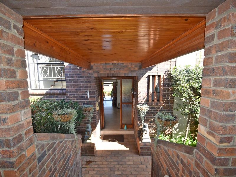 A covered brick entrance pathway leading to the front door, featuring a timber-lined ceiling and rustic brickwork construction.
