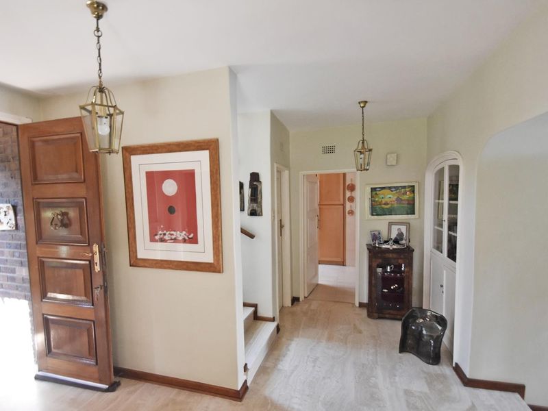 Welcoming entrance hall featuring stone flooring, a solid wood front door, built-in display cabinetry, and classic pendant lighting leading to the home's interior.