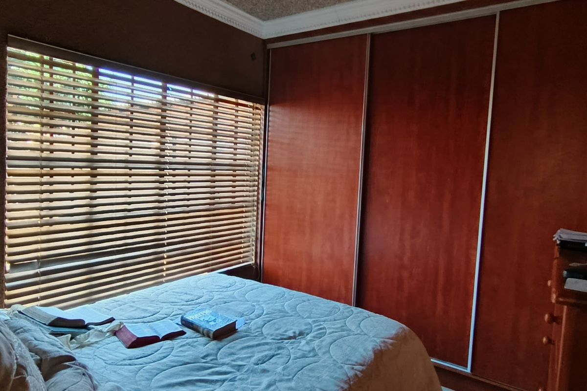 A bedroom featuring built-in wooden sliding door wardrobes, venetian blinds, and decorative ceiling cornicing.