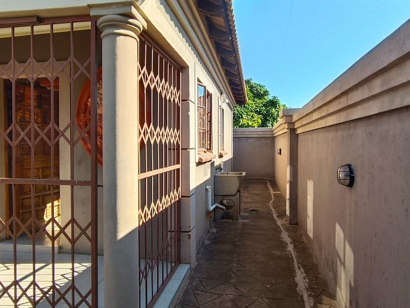 A side exterior walkway featuring a utility sink, security gates, and perimeter walling, providing functional access along the side of the house.