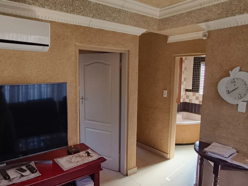 Open plan living area featuring textured wall finishes, crown molding, split-system air conditioning, and direct access to the kitchen and bathroom.