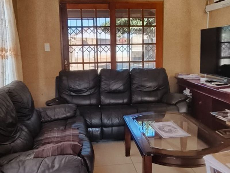 A living room featuring tiled flooring, a sliding glass door with security gate, and an air conditioning unit, finished with a textured ceiling.