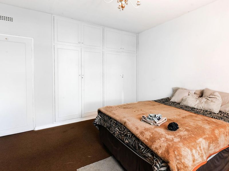 A bedroom featuring built-in cupboards and neutral wall finishes, providing a functional space with ample storage.