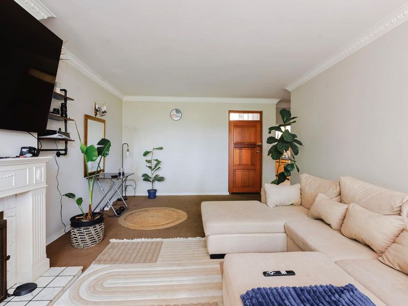 A living room featuring a fireplace with a mantelpiece, crown molding, and a solid timber front door.
