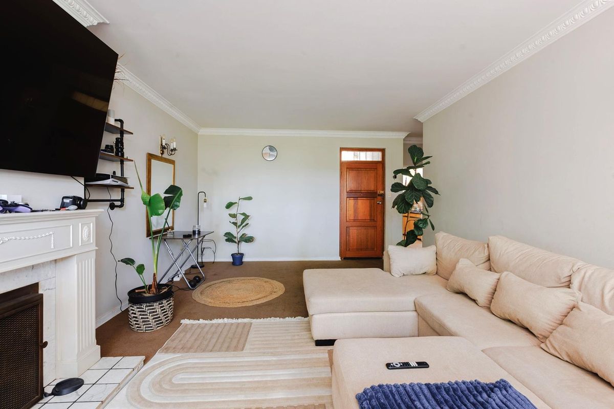 A living room featuring a fireplace with a mantelpiece, crown molding, and a solid timber front door.