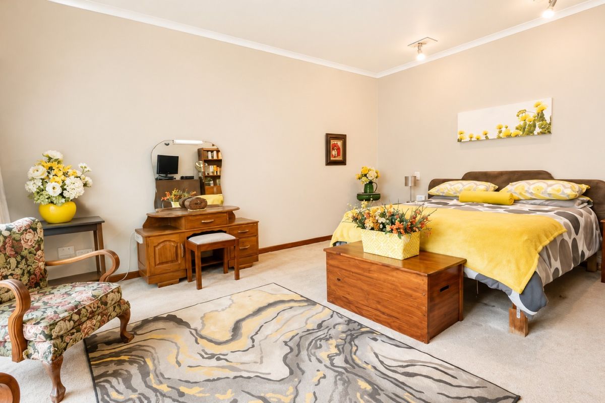 A spacious bedroom featuring neutral wall tones, carpeted flooring, and classic cove cornicing, offering a comfortable and well-maintained living space.