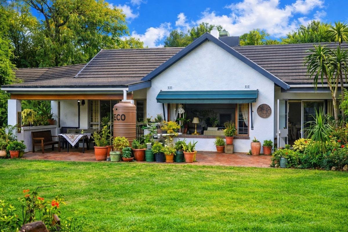 A well-maintained rear exterior view featuring a covered patio, brick paving, and a landscaped garden area.