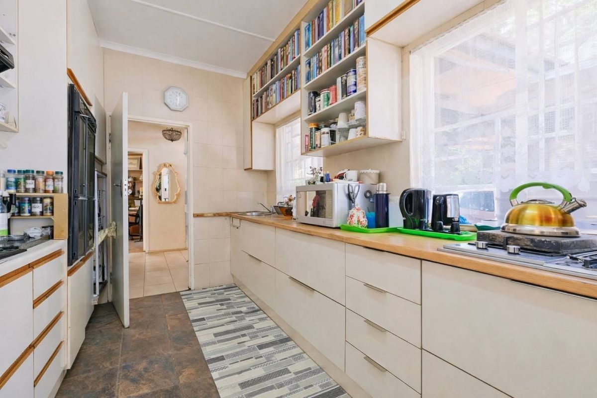 A functional kitchen featuring built-in cabinetry, laminate countertops, a gas hob, and an integrated oven, with ample overhead storage and tiled splashbacks.