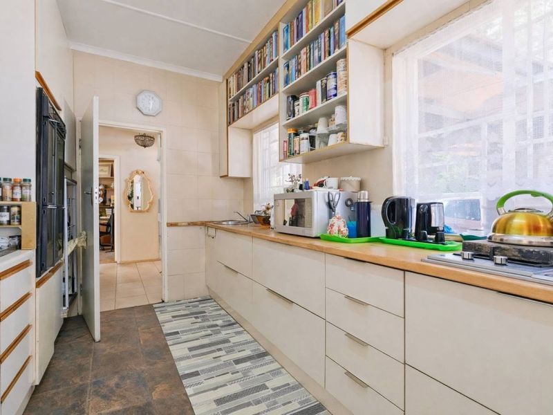 A functional kitchen featuring built-in cabinetry, laminate countertops, a gas hob, and an integrated oven, with ample overhead storage and tiled splashbacks.