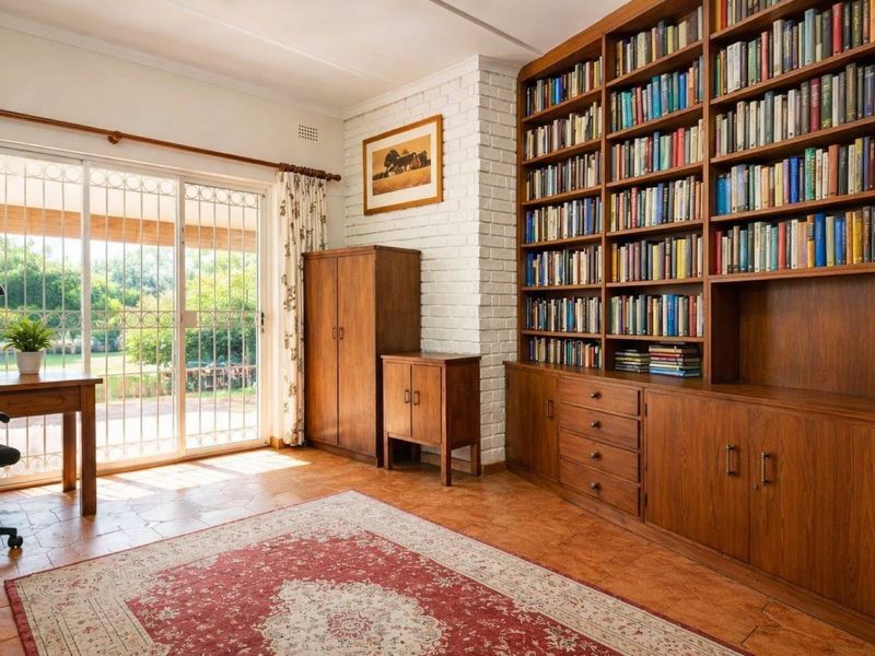 A bright living room featuring a large built-in wooden bookshelf, a painted brick fireplace, and sliding glass doors leading to the garden.