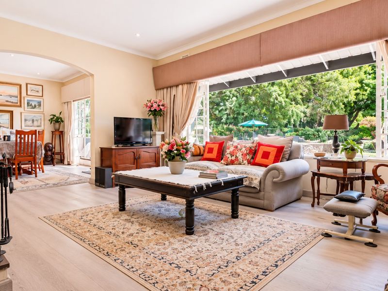 Spacious open-plan living and dining area featuring a fireplace, light laminate flooring, and large sliding doors opening to a lush garden view.
