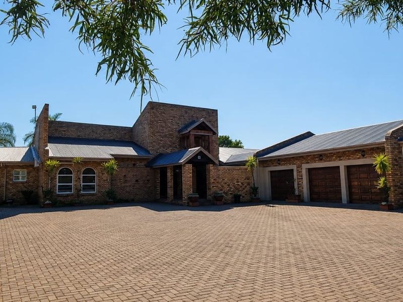 Spacious front exterior featuring a large paved driveway, face brick facade, and a triple garage with arched window detailing.
