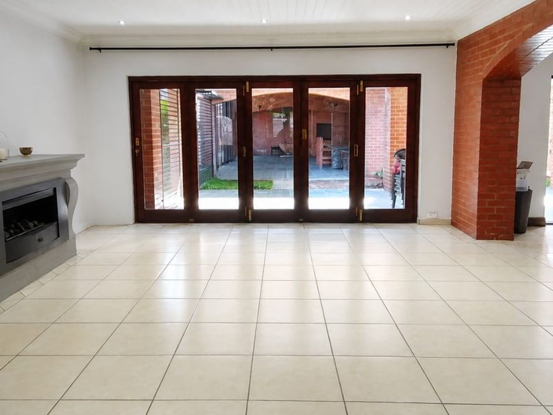 Spacious living area featuring tiled flooring, a built-in fireplace, and large bi-fold doors opening to an outdoor patio area.