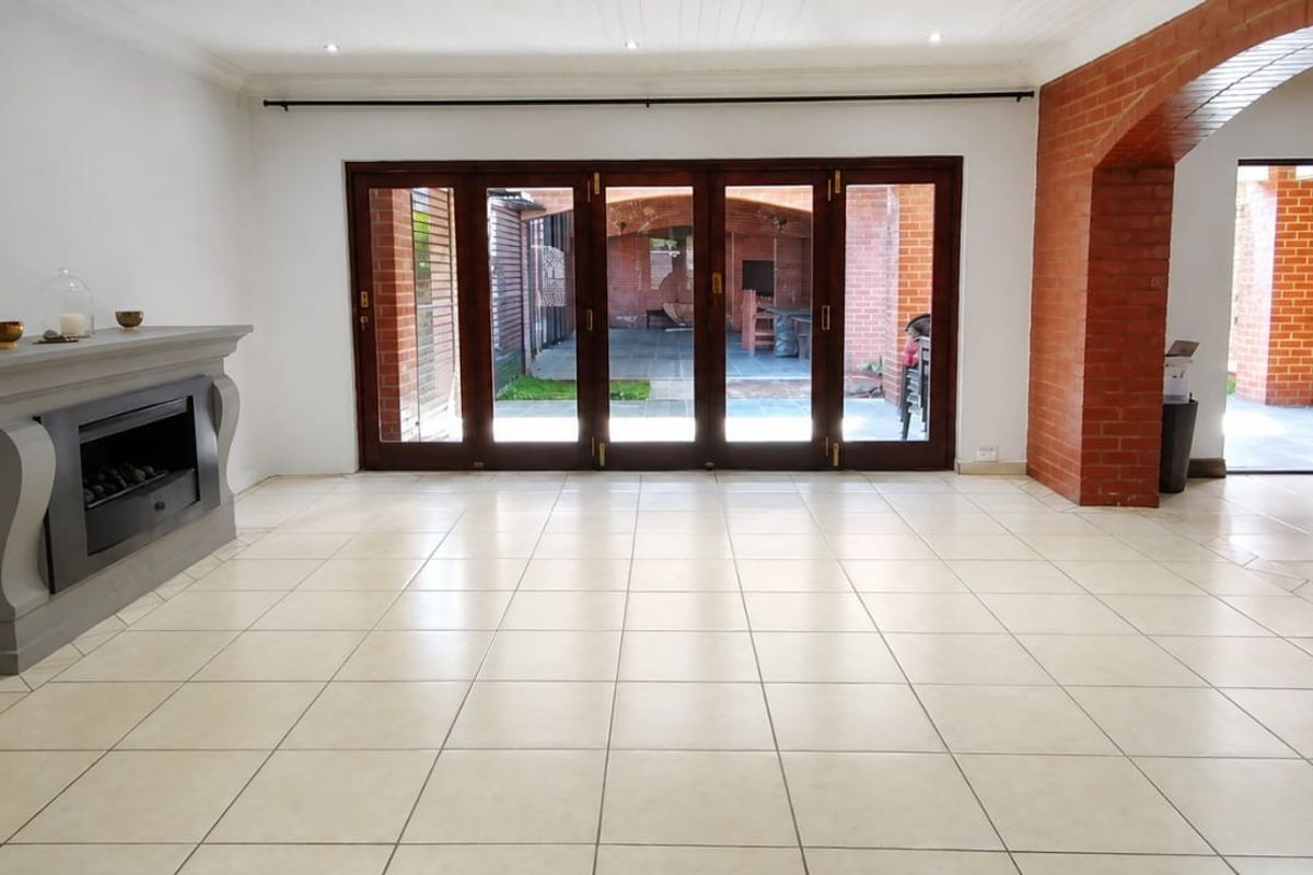 Spacious living area featuring tiled flooring, a built-in fireplace, and large bi-fold doors opening to an outdoor patio area.