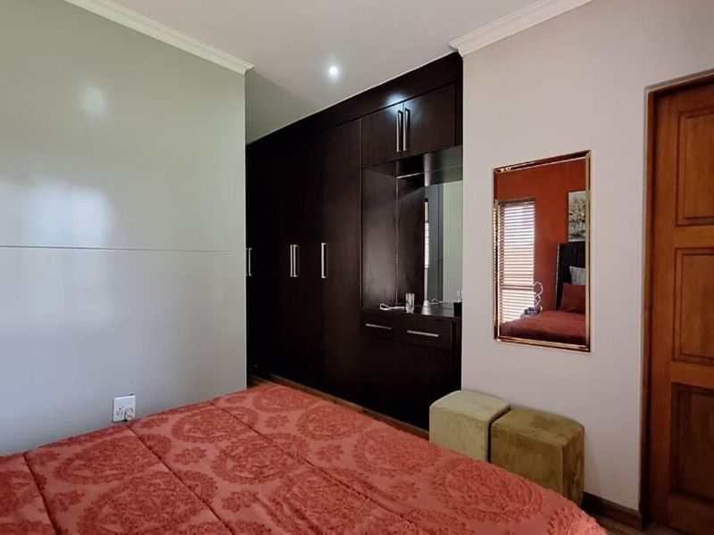 A well-maintained bedroom featuring dark wood built-in cupboards with an integrated vanity station and recessed lighting.