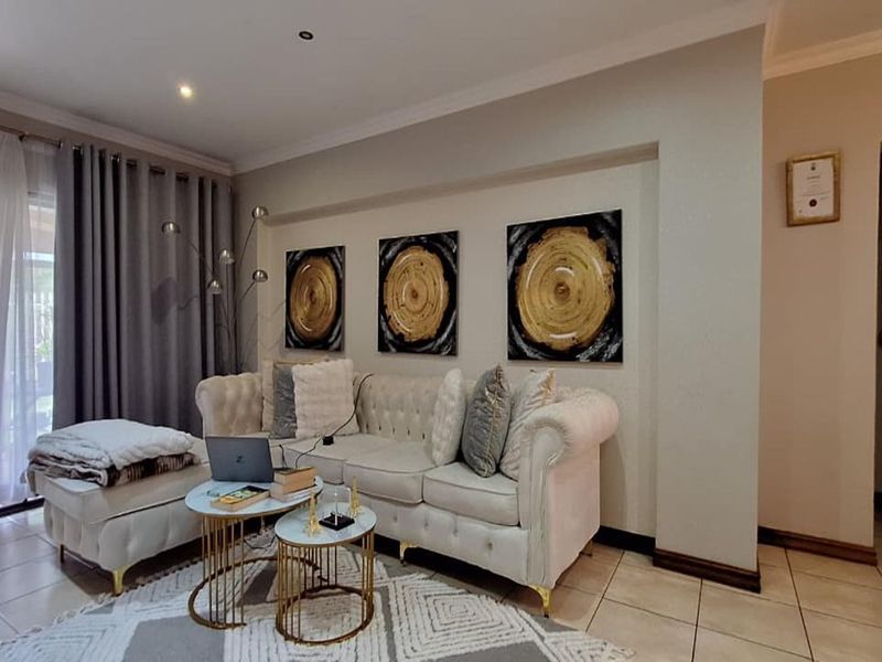 A well-maintained living room featuring neutral tiled flooring, recessed lighting, and a sliding glass door providing access to the outdoor area.