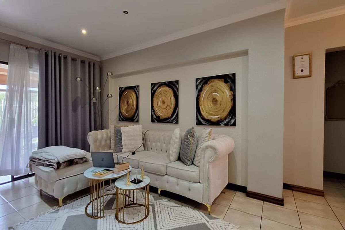 A well-maintained living room featuring neutral tiled flooring, recessed lighting, and a sliding glass door providing access to the outdoor area.