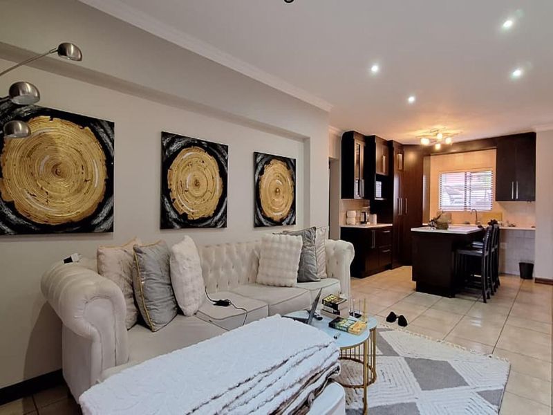 Open-plan living area featuring tiled floors, recessed lighting, and a modern kitchen with dark cabinetry and a central island.