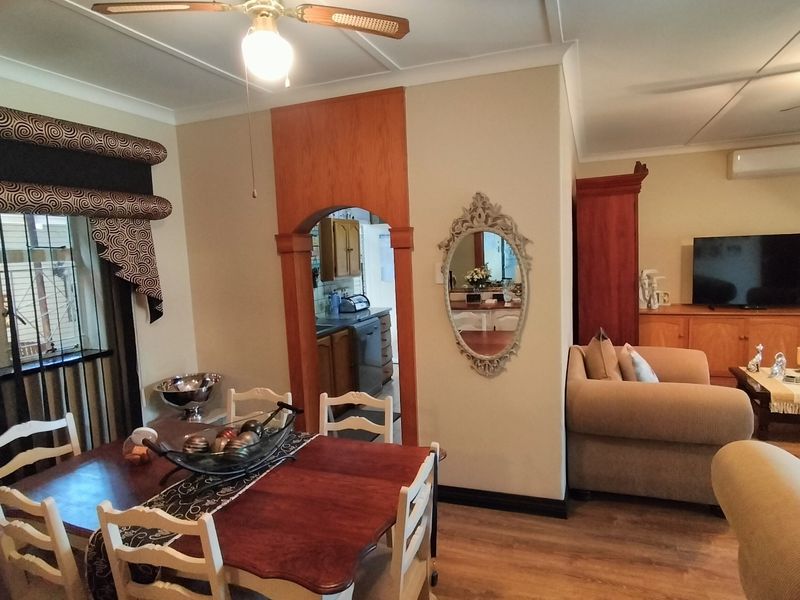 Open plan living and dining area featuring laminate flooring, ceiling fans, and a distinct arched entryway leading to the kitchen.