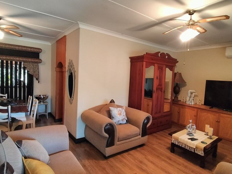 Open-plan living and dining area featuring laminate flooring, ceiling fans, and built-in cabinetry, providing a functional and connected living space.