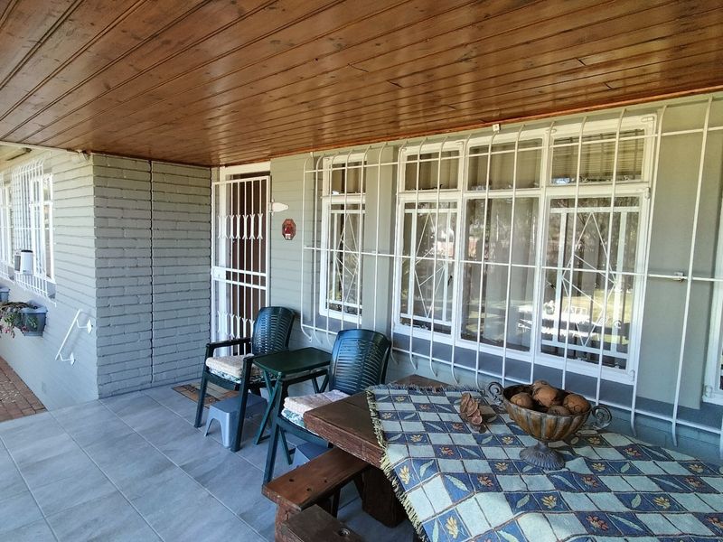 A covered patio area featuring a timber ceiling, tiled flooring, and security bars on the windows and doors.