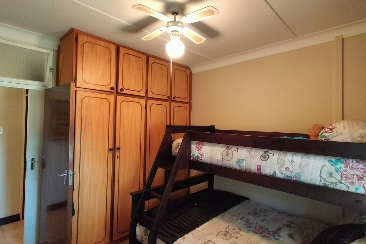 A bedroom featuring floor-to-ceiling built-in wooden cabinetry and a central ceiling fan.