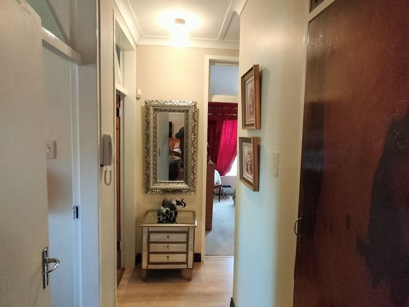 A functional residential hallway featuring laminate flooring, coving, and an intercom system, providing access to adjacent rooms.
