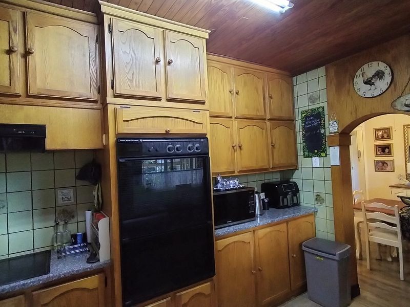 A traditional kitchen featuring extensive wooden cabinetry, a built-in oven, and a timber ceiling, offering a classic aesthetic with potential for modern updates.