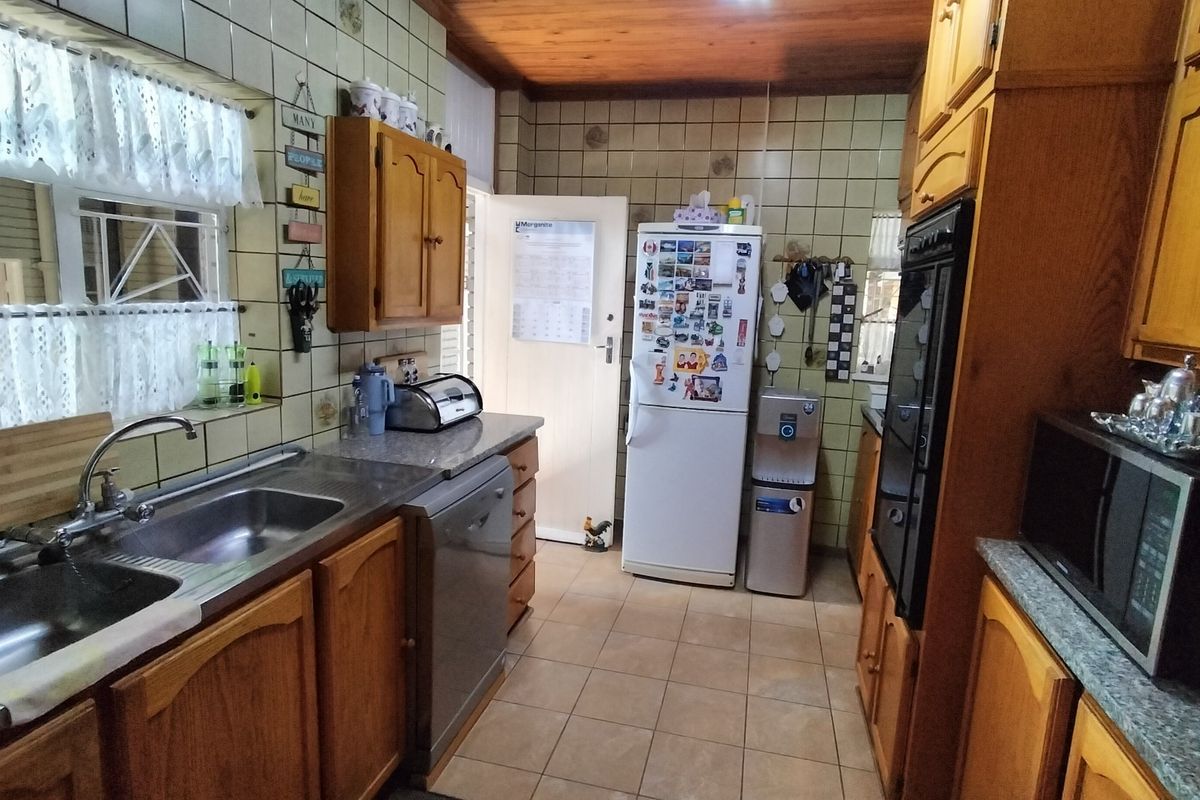 A functional kitchen featuring timber cabinetry, tiled splashbacks, and a timber ceiling, offering a traditional aesthetic with potential for modern updates.