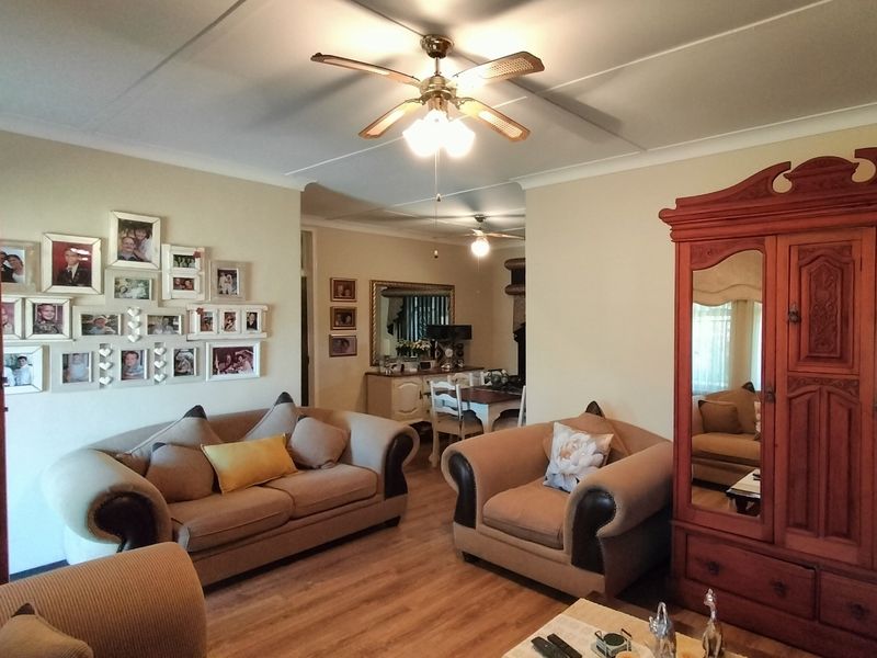A comfortable living room featuring laminate flooring, a ceiling fan, and coved ceilings, providing a warm and inviting atmosphere.