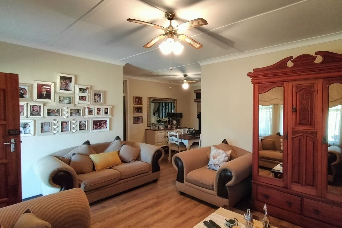 A comfortable living room featuring laminate flooring, a ceiling fan, and coved ceilings, providing a warm and inviting atmosphere.
