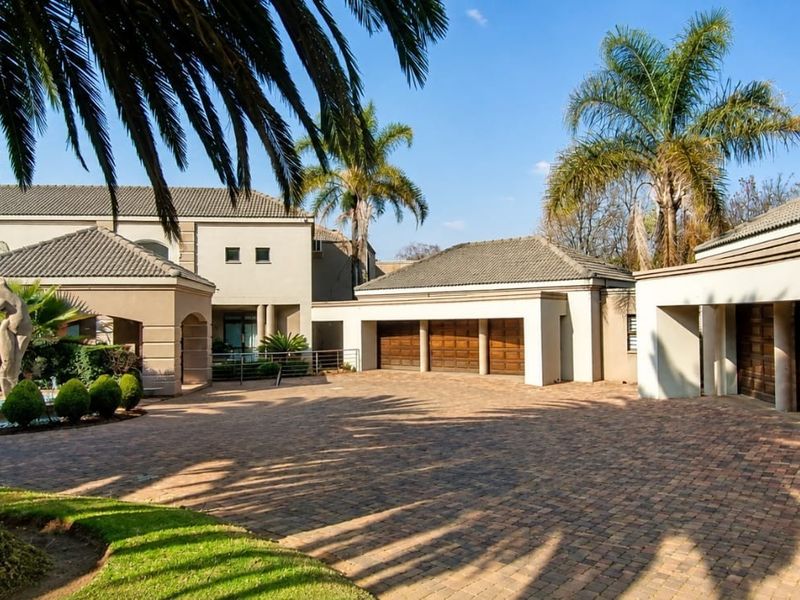Spacious front exterior featuring a large paved driveway, multiple garage bays, and a well-maintained garden with a decorative water fountain.