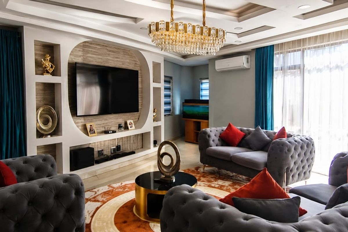 Spacious living room featuring a custom built-in media wall, elegant coffered ceiling with recessed lighting, and a sophisticated crystal chandelier.