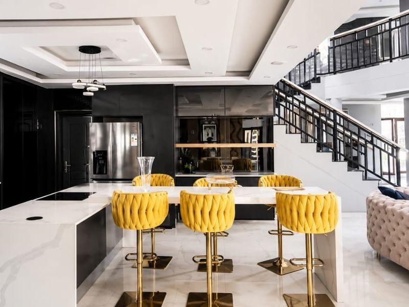 Modern open-plan living area featuring a sleek kitchen with a large island, high-end finishes, and a striking staircase with contemporary metal railings.
