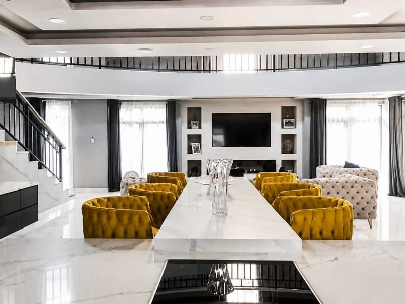 Spacious open-plan living and kitchen area featuring a large marble island, modern built-in cabinetry, recessed lighting, and a grand staircase.