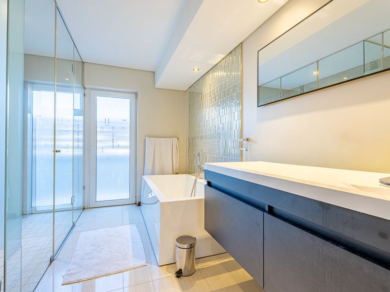Modern bathroom featuring a sleek freestanding bathtub, wall-mounted vanity, glass shower enclosure, and a stylish mosaic tile feature wall.