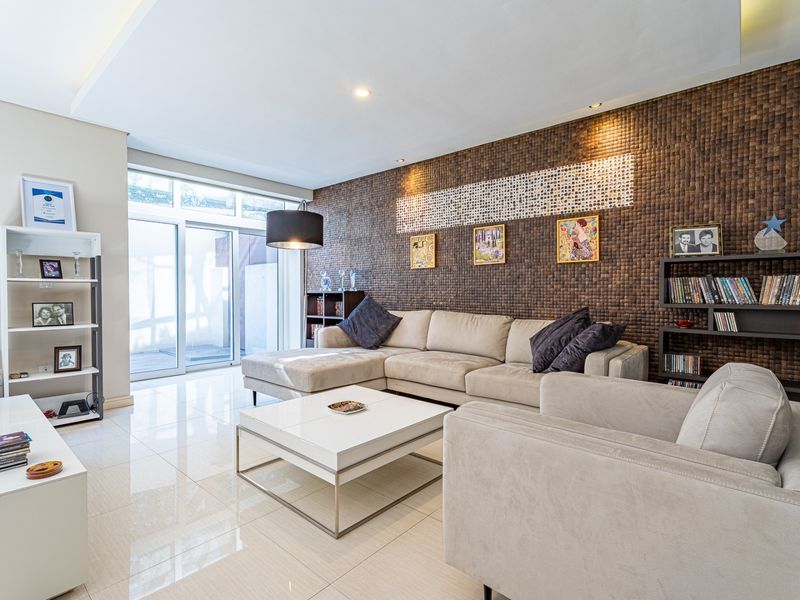 A modern living room featuring polished tile flooring, a textured feature wall, and large sliding glass doors providing natural light and access to the exterior.