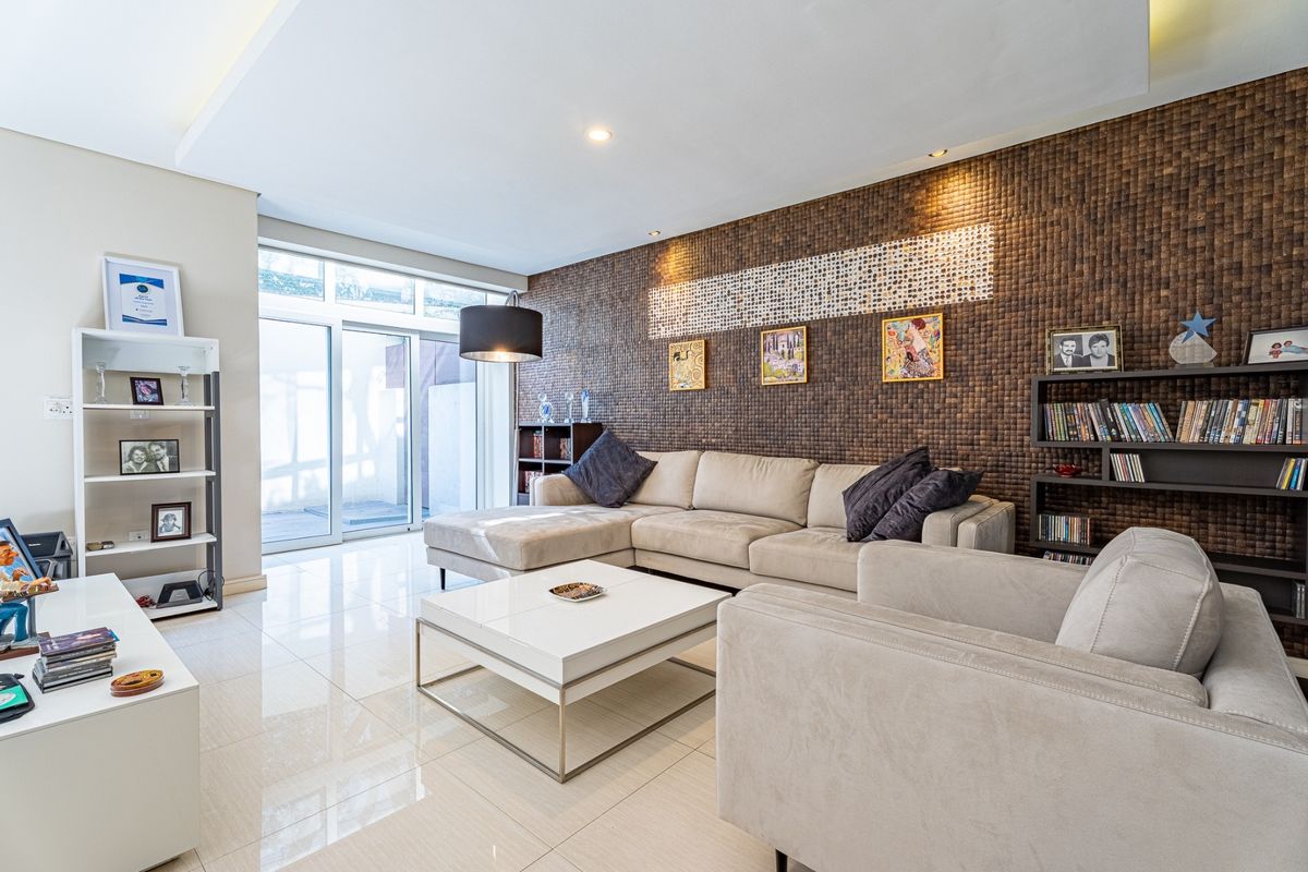 A modern living room featuring polished tile flooring, a textured feature wall, and large sliding glass doors providing natural light and access to the exterior.