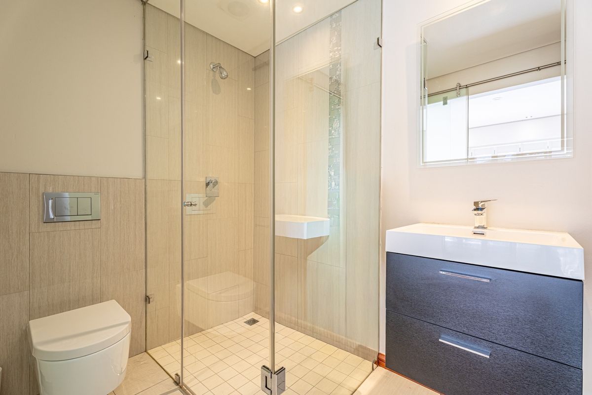 Modern bathroom featuring a glass-enclosed shower, wall-hung toilet, and a contemporary vanity with basin.