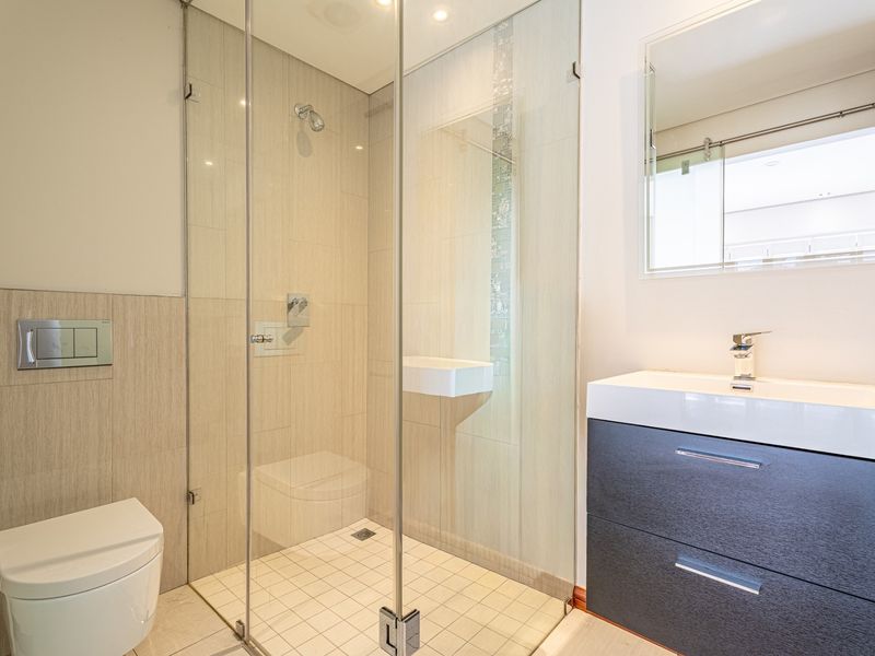 Modern bathroom featuring a glass-enclosed shower, wall-hung toilet, and a contemporary vanity with basin.