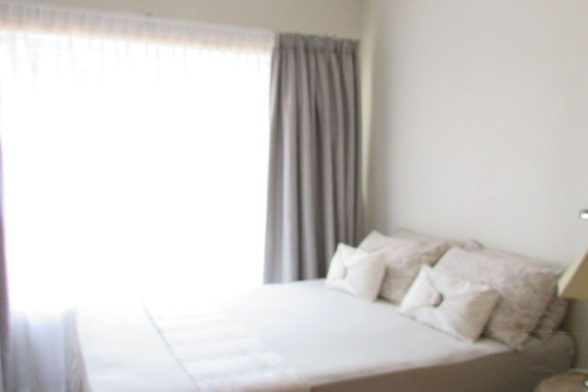 A bedroom featuring tiled flooring, a ceiling fan, and neutral wall finishes with natural light from the window.