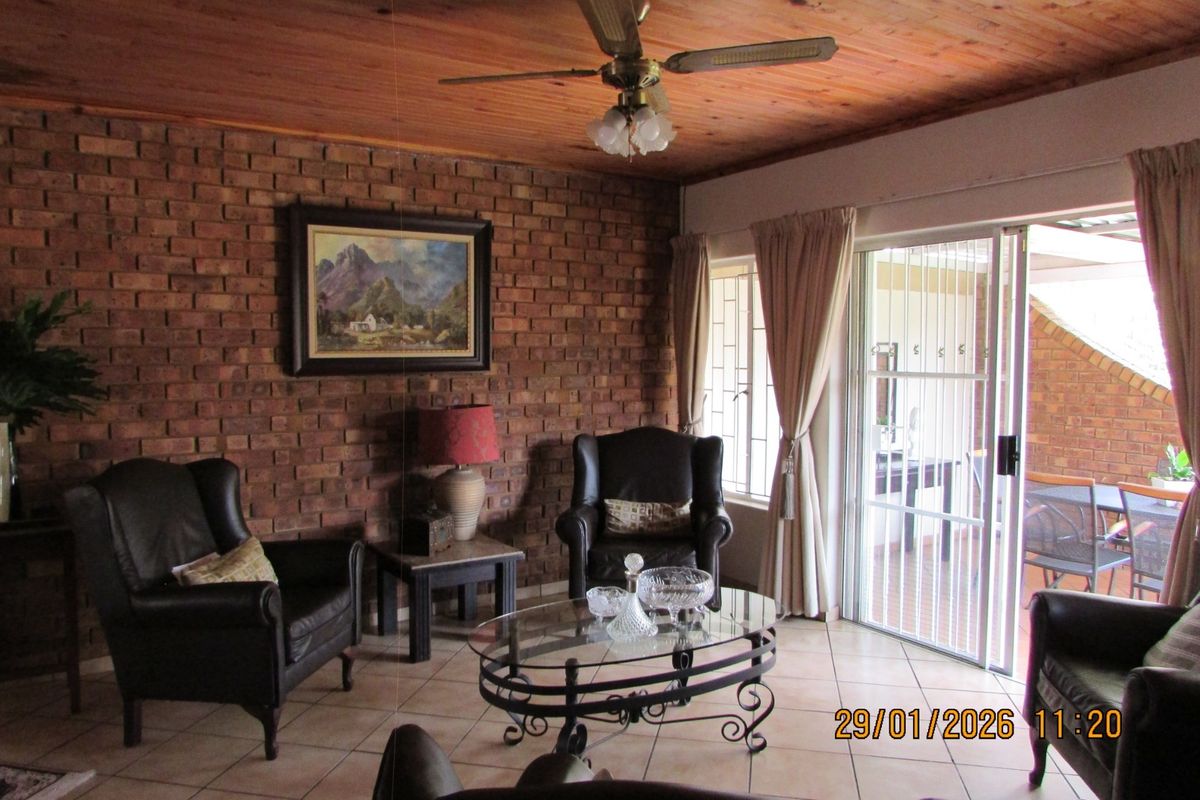 Living room featuring an exposed brick feature wall, timber ceiling, and tiled flooring, with direct access to an outdoor patio area.